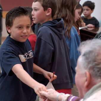 Young student shakes hands with male Jewish Home resident
