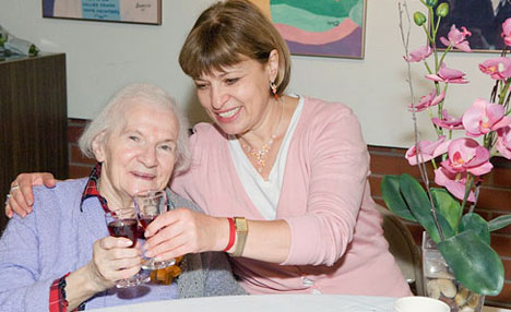 Resident and staff member at a birthday luncheon, making a toast