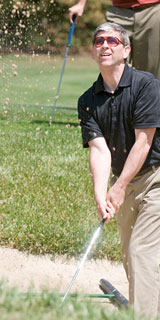 Man looking out at the flying ball from a sand trap