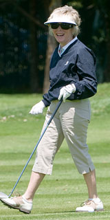 Woman in sunglasses and visor with club walking on a green