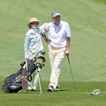 Couple standing with golf equipment on the green